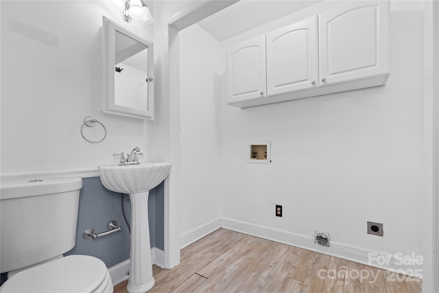 half bathroom featuring toilet, baseboards, and wood finished floors