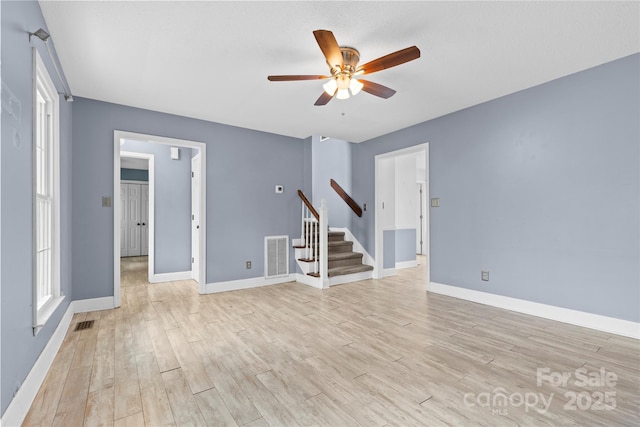 unfurnished room with visible vents, ceiling fan, stairs, and light wood-style flooring