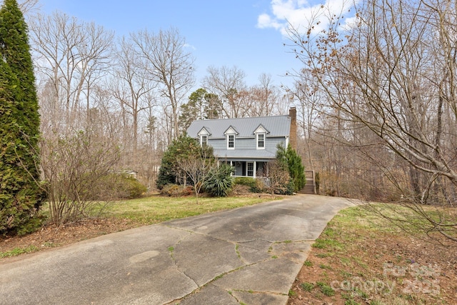 view of front of property featuring driveway, metal roof, and a front lawn