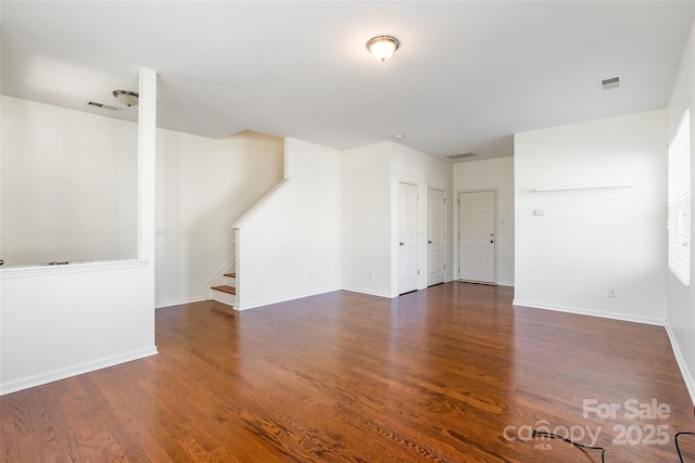 unfurnished living room featuring stairs, wood finished floors, visible vents, and baseboards