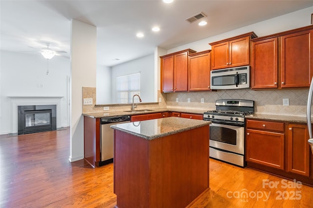 kitchen featuring visible vents, light wood finished floors, a sink, appliances with stainless steel finishes, and a center island