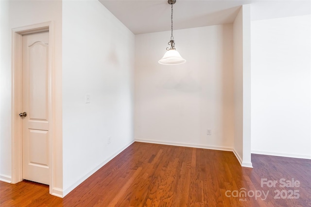 unfurnished dining area featuring wood finished floors and baseboards