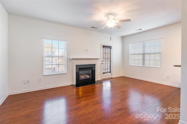 unfurnished living room featuring wood-type flooring, plenty of natural light, and ceiling fan