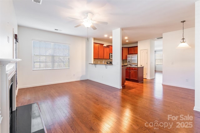 unfurnished living room with a fireplace with flush hearth, baseboards, ceiling fan, and dark wood-style flooring