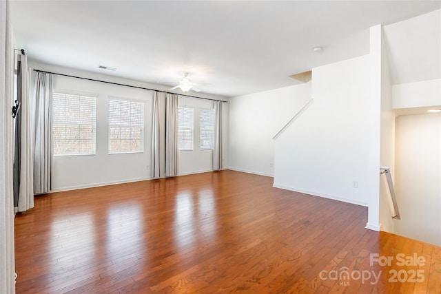 unfurnished living room featuring hardwood / wood-style flooring, baseboards, visible vents, and ceiling fan