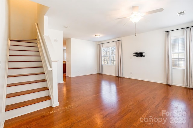 unfurnished living room with visible vents, baseboards, stairs, wood finished floors, and a ceiling fan