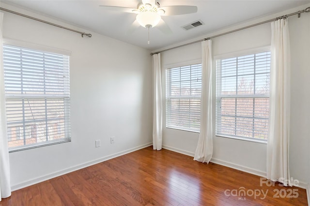 empty room with visible vents, plenty of natural light, ceiling fan, and wood finished floors