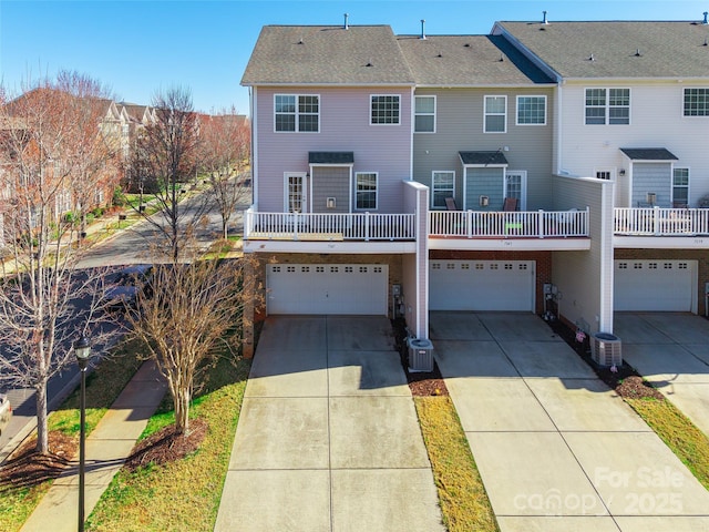 back of property featuring an attached garage, cooling unit, and driveway