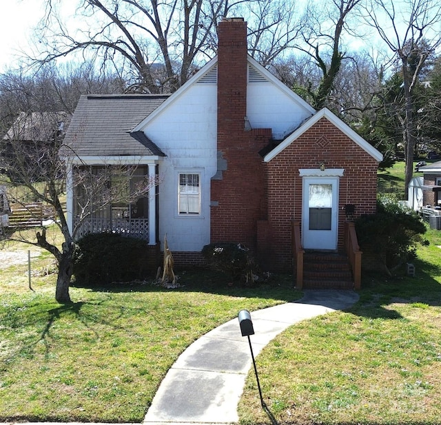 view of front of home featuring a chimney, entry steps, concrete block siding, and a front lawn