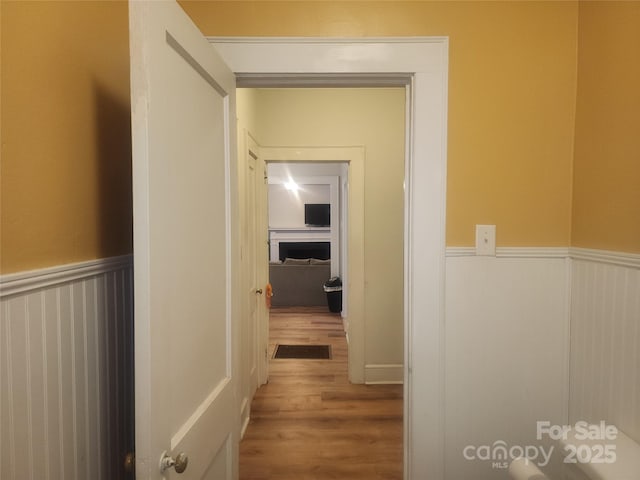 corridor with wood finished floors and wainscoting