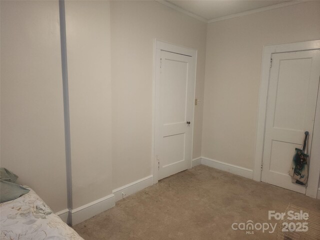 unfurnished bedroom featuring baseboards, crown molding, and carpet