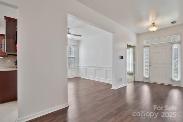 entrance foyer with a decorative wall, visible vents, a ceiling fan, and wood finished floors