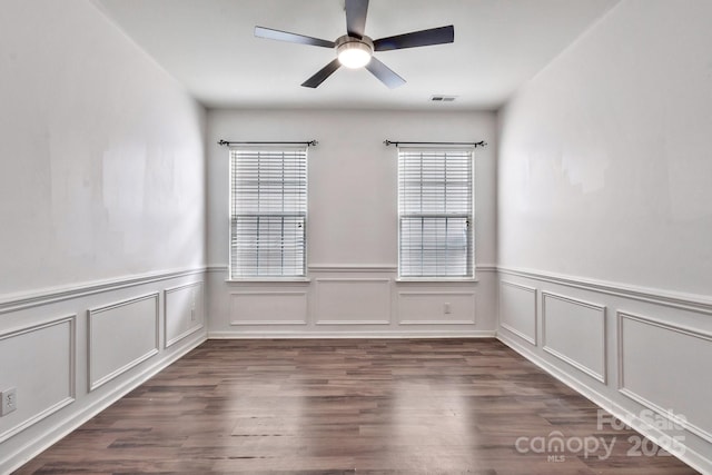 unfurnished room with visible vents, dark wood-style flooring, and a ceiling fan