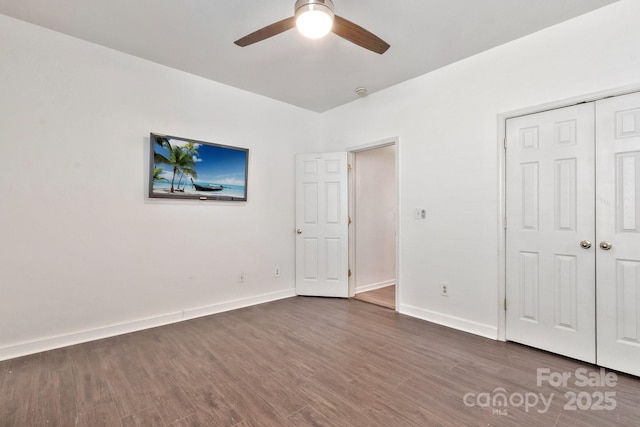 unfurnished bedroom featuring a closet, ceiling fan, baseboards, and wood finished floors