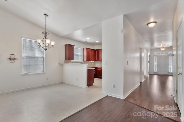 kitchen featuring wood finished floors, baseboards, dark brown cabinets, decorative light fixtures, and a notable chandelier