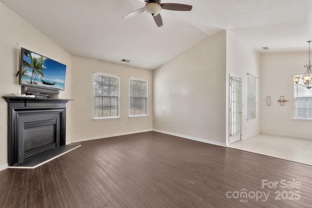 unfurnished living room with plenty of natural light, ceiling fan with notable chandelier, and wood finished floors