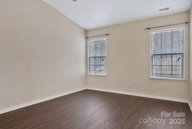 unfurnished room featuring visible vents, baseboards, and dark wood-style flooring