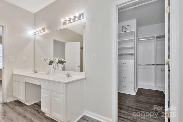 bathroom with double vanity, wood finished floors, baseboards, and a sink