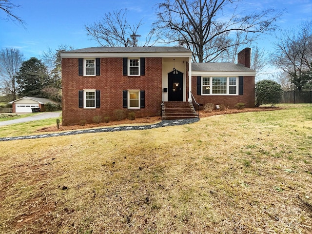 view of front of property with a front yard, brick siding, a chimney, and fence