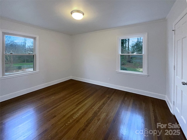 unfurnished bedroom with dark wood finished floors, multiple windows, baseboards, and ornamental molding