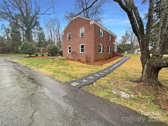 view of side of property with brick siding and a lawn