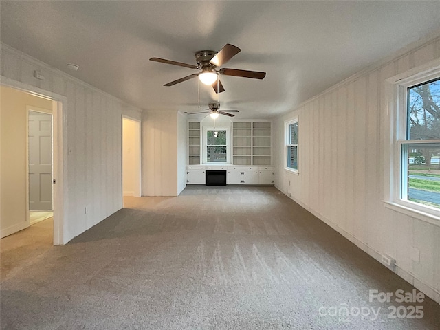 unfurnished living room featuring carpet flooring, built in shelves, and ornamental molding