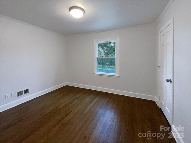 spare room featuring dark wood finished floors, crown molding, baseboards, and visible vents