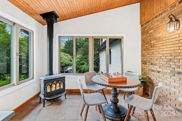 sunroom with vaulted ceiling, a wood stove, and wood ceiling