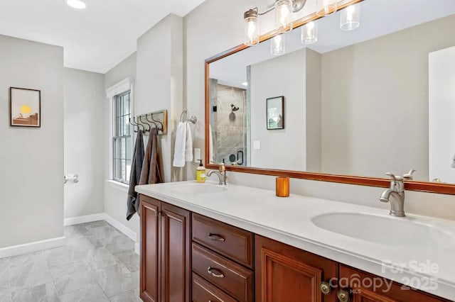 full bathroom with a sink, baseboards, double vanity, and a shower stall