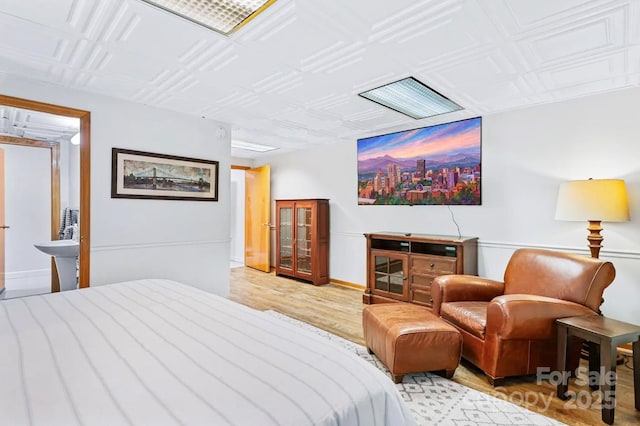 bedroom with baseboards, an ornate ceiling, and light wood-style flooring