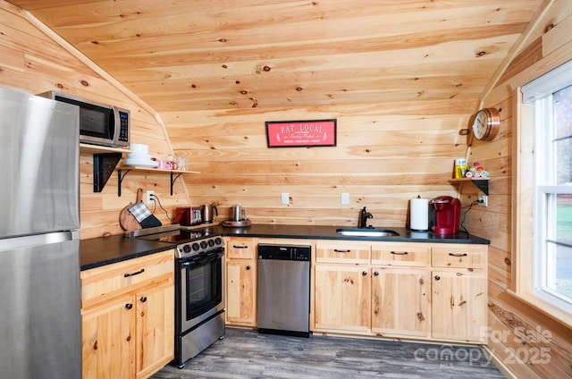 kitchen featuring wooden walls, light brown cabinets, and stainless steel appliances