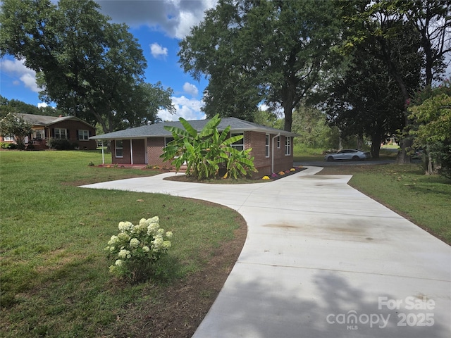 view of front facade with a front lawn, brick siding, and driveway