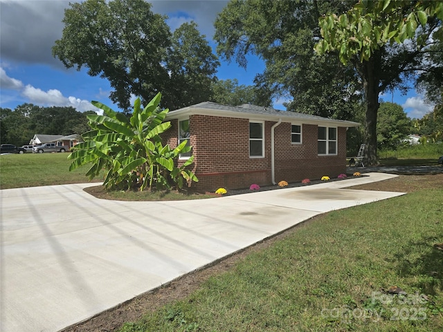 view of property exterior featuring a yard, brick siding, and driveway