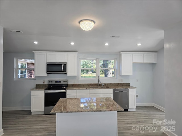 kitchen featuring visible vents, white cabinets, stainless steel appliances, and a sink