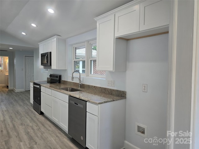 kitchen with white cabinetry, stone countertops, stainless steel appliances, and a sink