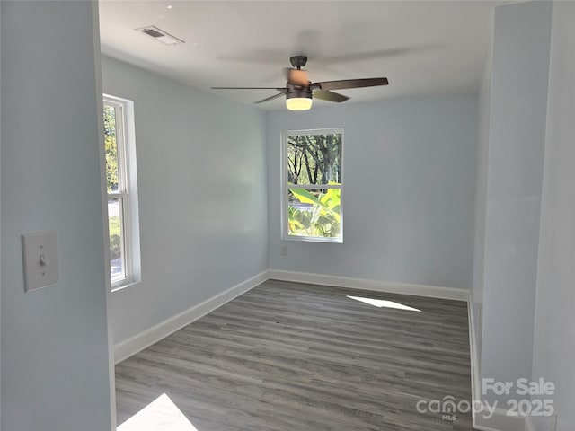 empty room with visible vents, a ceiling fan, baseboards, and wood finished floors