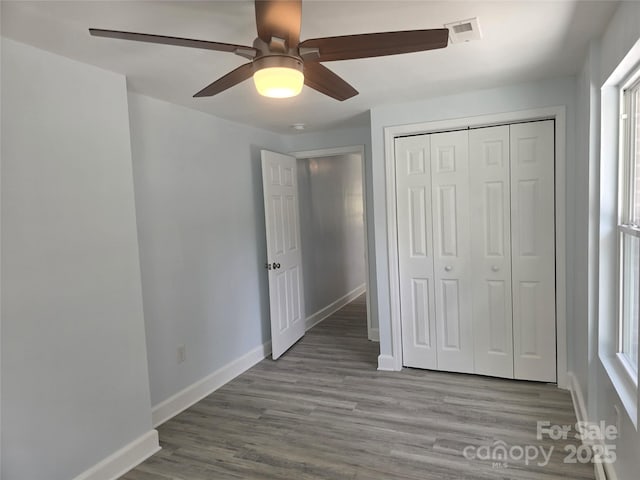 unfurnished bedroom with visible vents, a ceiling fan, wood finished floors, a closet, and baseboards