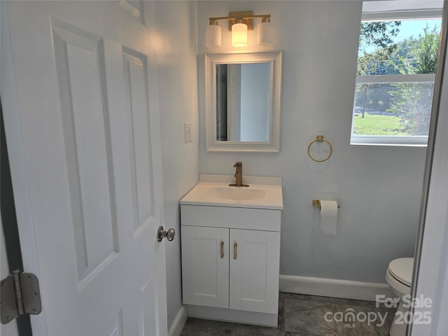 half bath with baseboards, toilet, and vanity