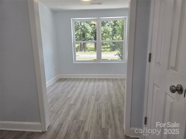 unfurnished room featuring visible vents, baseboards, and wood finished floors