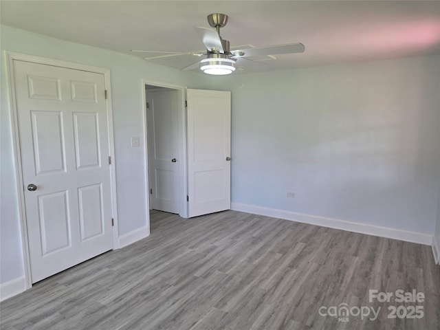 unfurnished bedroom featuring wood finished floors, baseboards, and ceiling fan