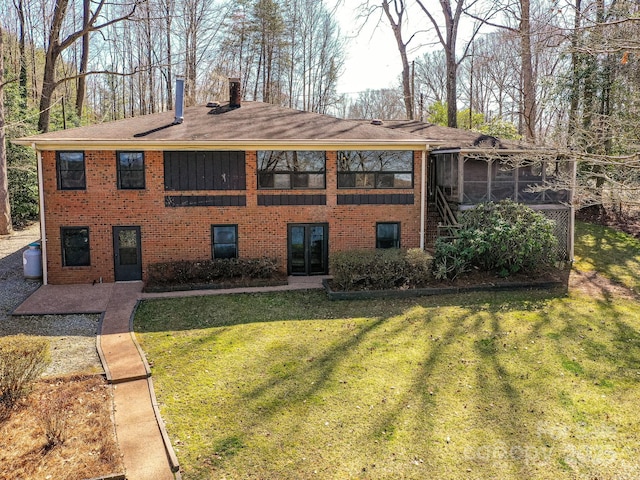 back of house with brick siding, a chimney, a yard, and a sunroom