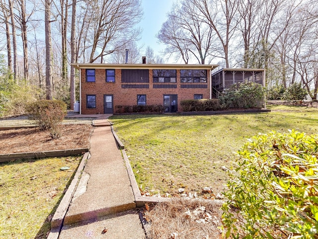 back of house with a yard, brick siding, and a sunroom