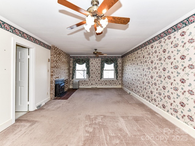 unfurnished living room with crown molding, wallpapered walls, a wood stove, and carpet