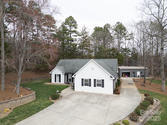 view of front of property featuring concrete driveway, a front lawn, roof with shingles, and stucco siding