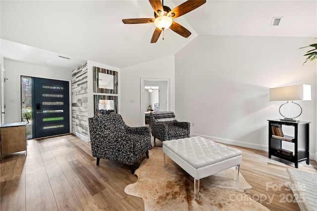 living area featuring visible vents, light wood-style floors, a ceiling fan, and vaulted ceiling