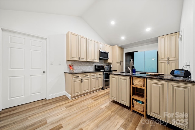 kitchen with cream cabinetry, stainless steel appliances, light wood-type flooring, and vaulted ceiling