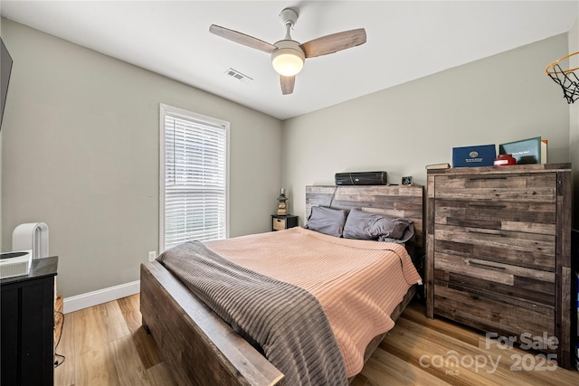 bedroom featuring a ceiling fan, baseboards, visible vents, and light wood finished floors