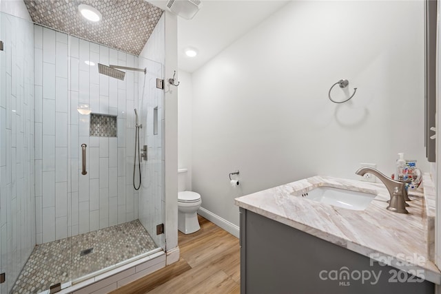 bathroom with vanity, wood finished floors, baseboards, a shower stall, and toilet