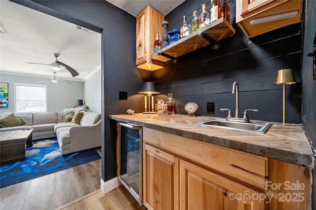 kitchen featuring visible vents, a sink, butcher block countertops, wine cooler, and light wood-style floors