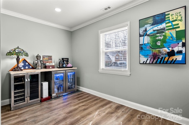 bar featuring visible vents, ornamental molding, wine cooler, a bar, and baseboards